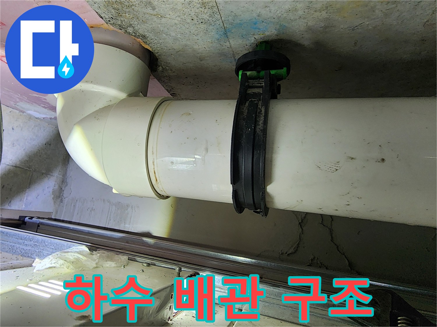 천장 내부의 굴곡진 하수 배관과 고정용 클램프 이미지입니다.