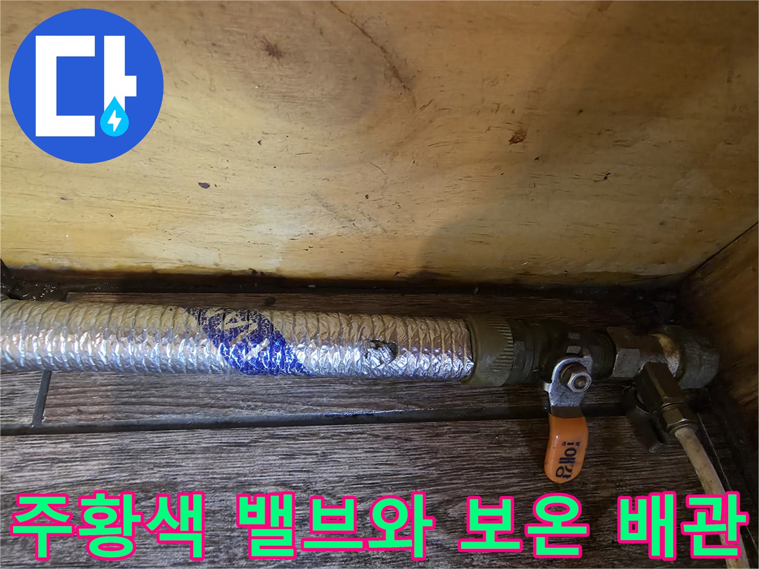 보온재로 감싸진 배관과 연결된 주황색 수동 밸브