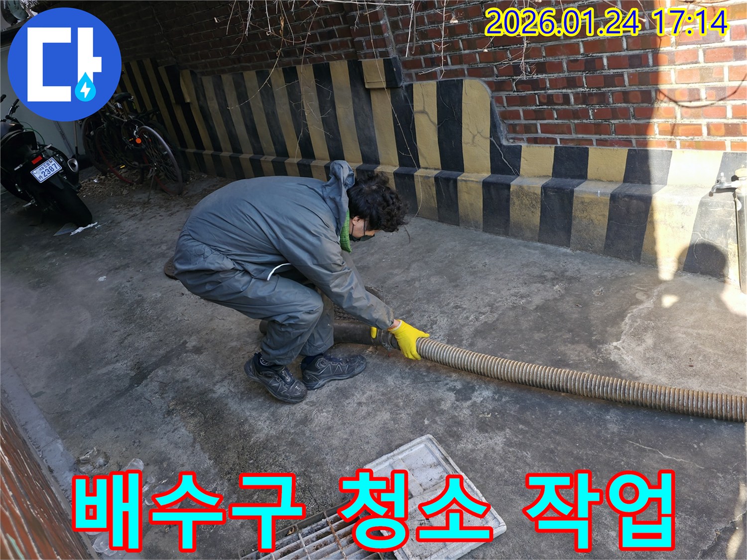 누수 엔지니어가 배수구 주변을 정리하고 호스를 이용해 청소 작업을 진행하고 있습니다 - 깨끗한 배수 환경은 누수 예방의 시작입니다.