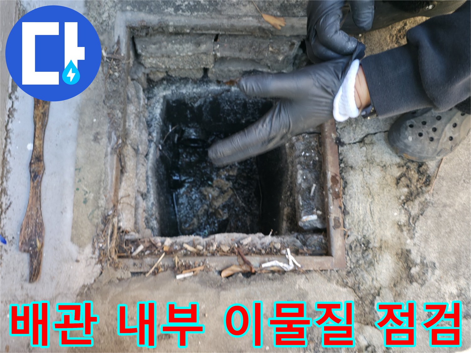 맨홀 덮개 사이로 보이는 오염된 배관 통로와 퇴적물