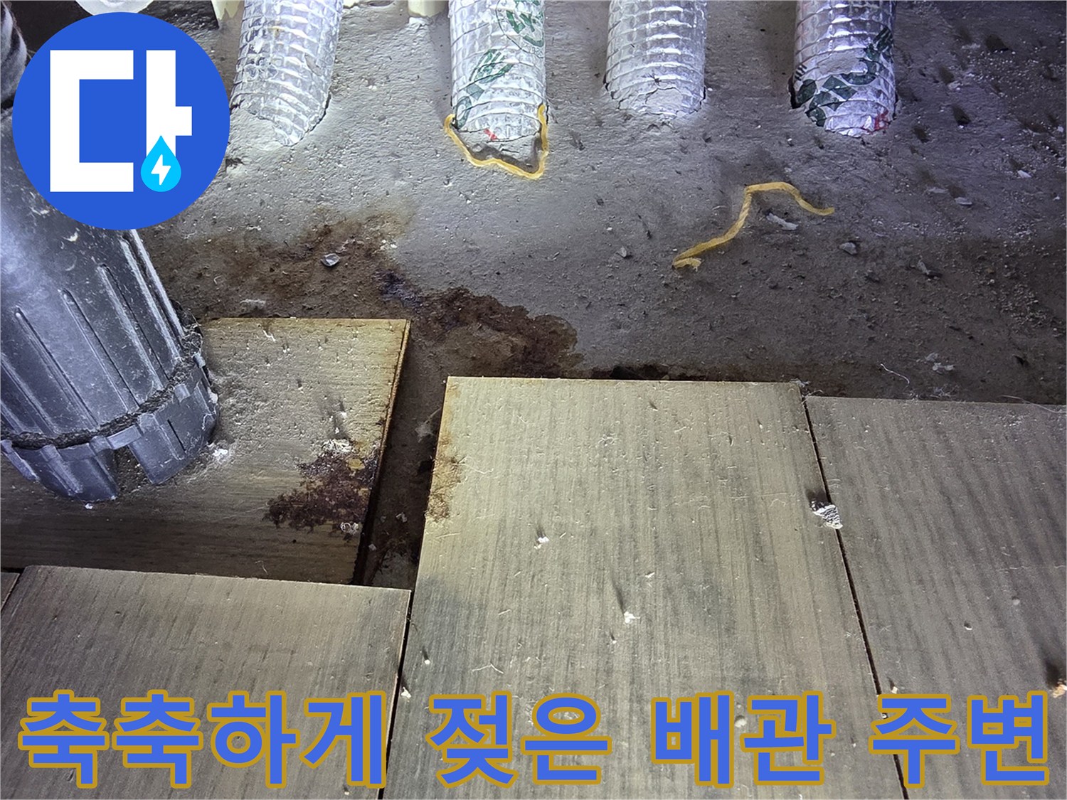 싱크대 하부 배관 주위의 젖은 바닥과 오염된 마루 표면을 보여줍니다.