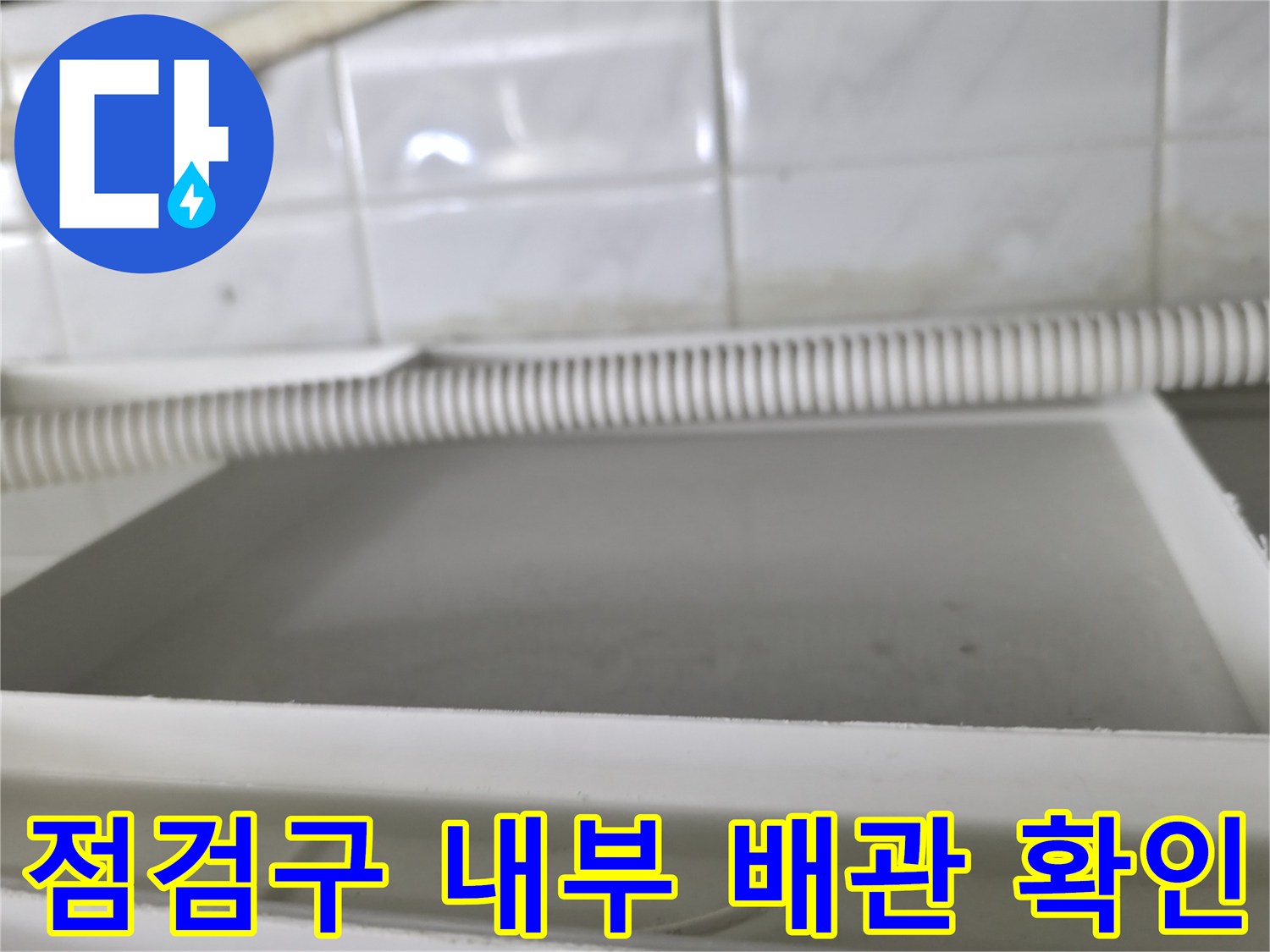 화장실 점검구 내부의-흰색 주름관과 천장 구조물 모습