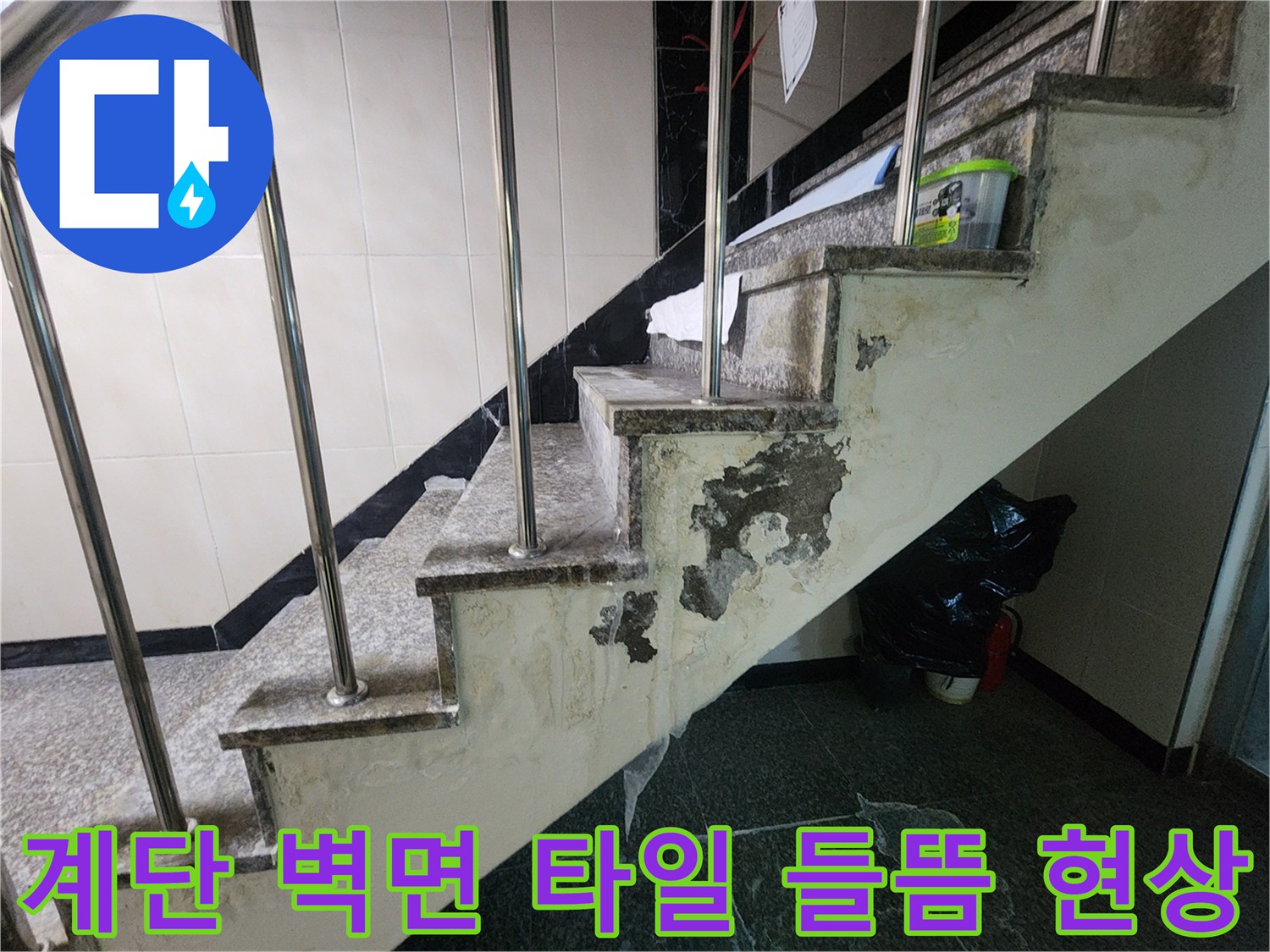 습기가 차올라 변색된 계단 옆 벽면 마감재의 모습