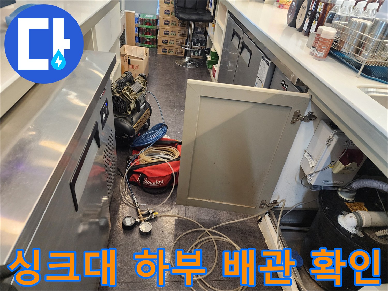 주방 싱크대 하부 공간-복잡한 설비 주변의 누수 여부 점검 중