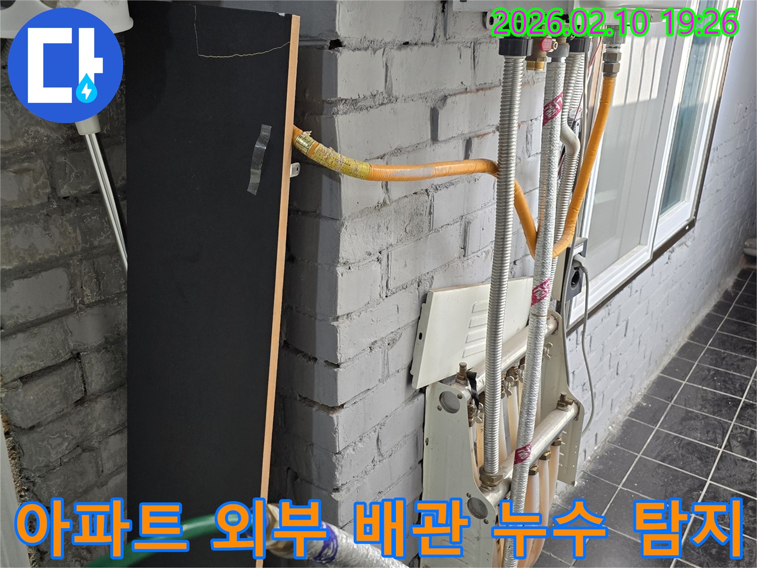 아파트 외벽에 설치된 배관에서-누수가 의심되어-전문 장비로 누수 위치를 파악하는 모습