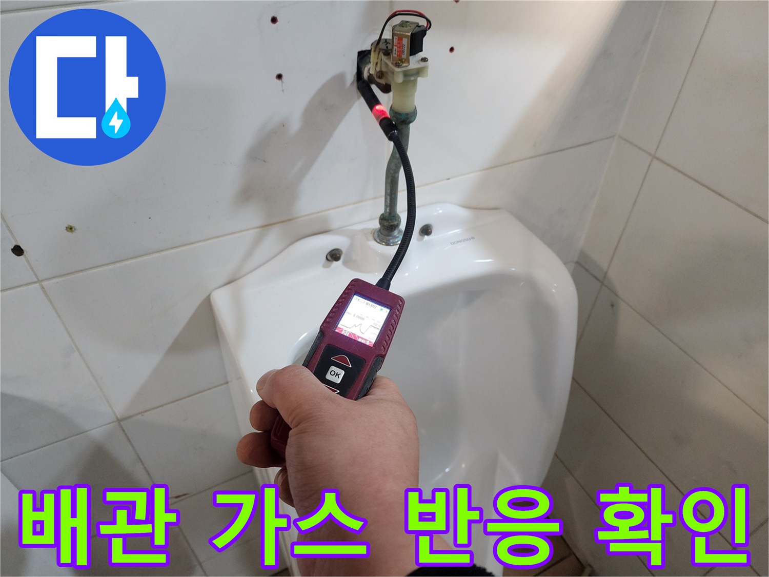 화장실 벽면 하단에서 가스 탐지기를 사용하여 배관의 누출 지점을 점검합니다.