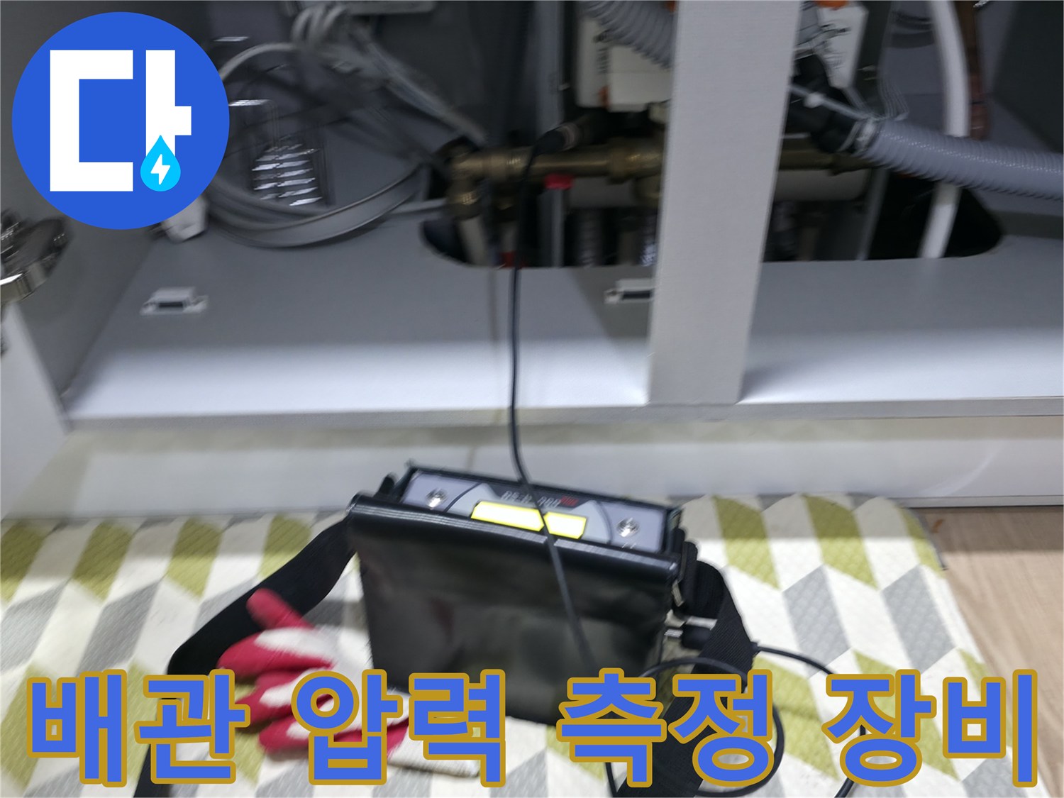 싱크대 하부장 내부에서 진행 중인 배관 공압 테스트 장비 모습