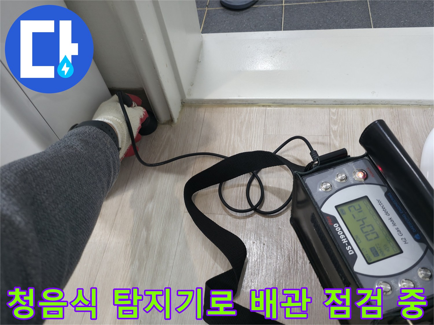 배관의 미세한 소리를 찾기 위해-청음식 탐지기를 사용하여-화장실 바닥 근처를 정밀하게 점검하는 모습입니다.