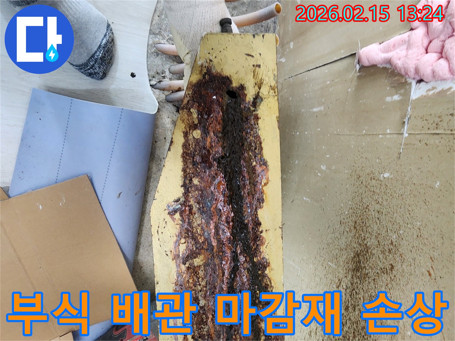 부식된-배관에서-발생한-누수로-인해-주변-마감재가-손상된-모습을-전문가가-점검하고-있습니다