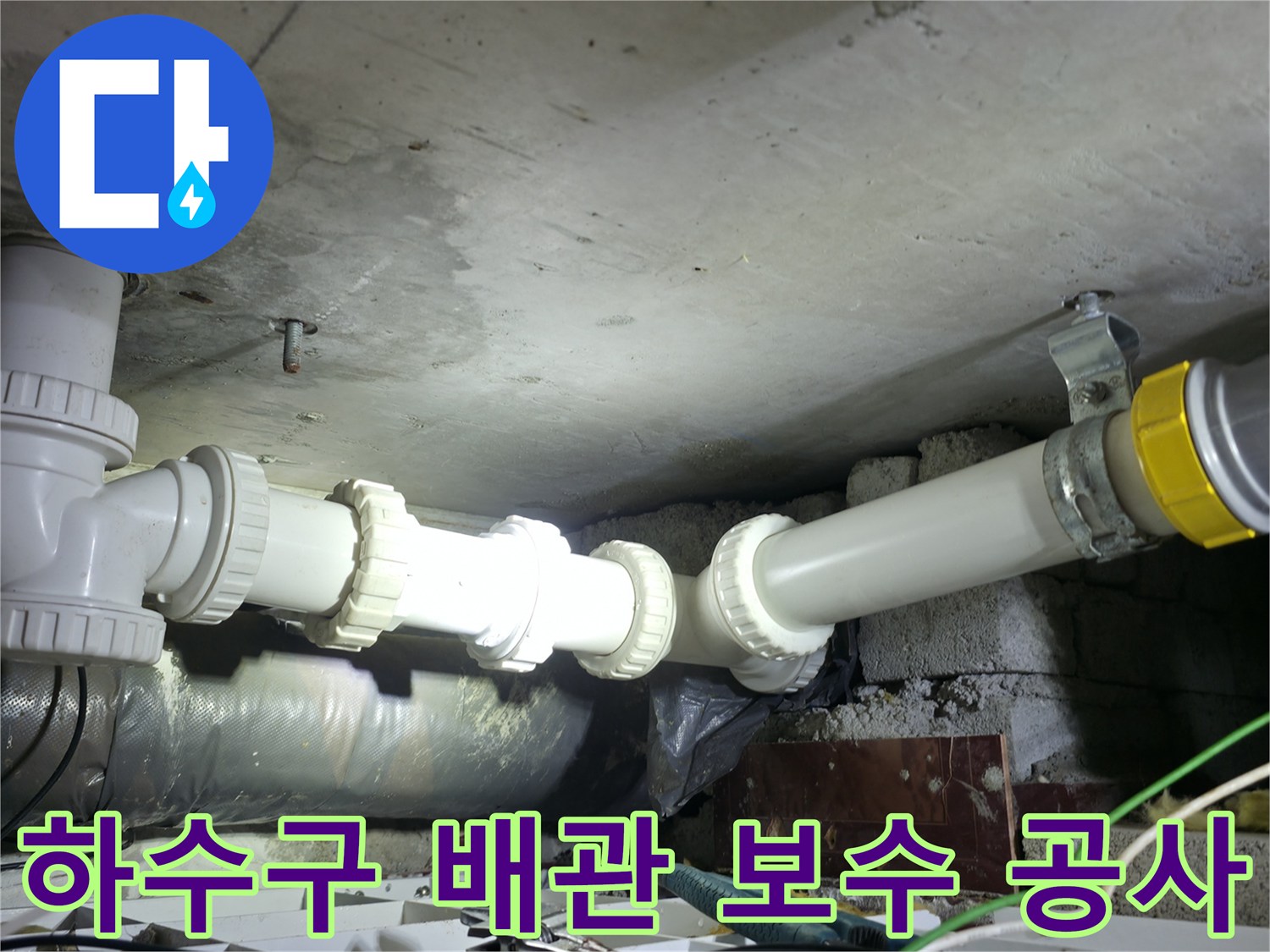 천장에 매달린 하수 배관의 연결 부위를 새 제품으로 교체하는 시공 장면입니다.