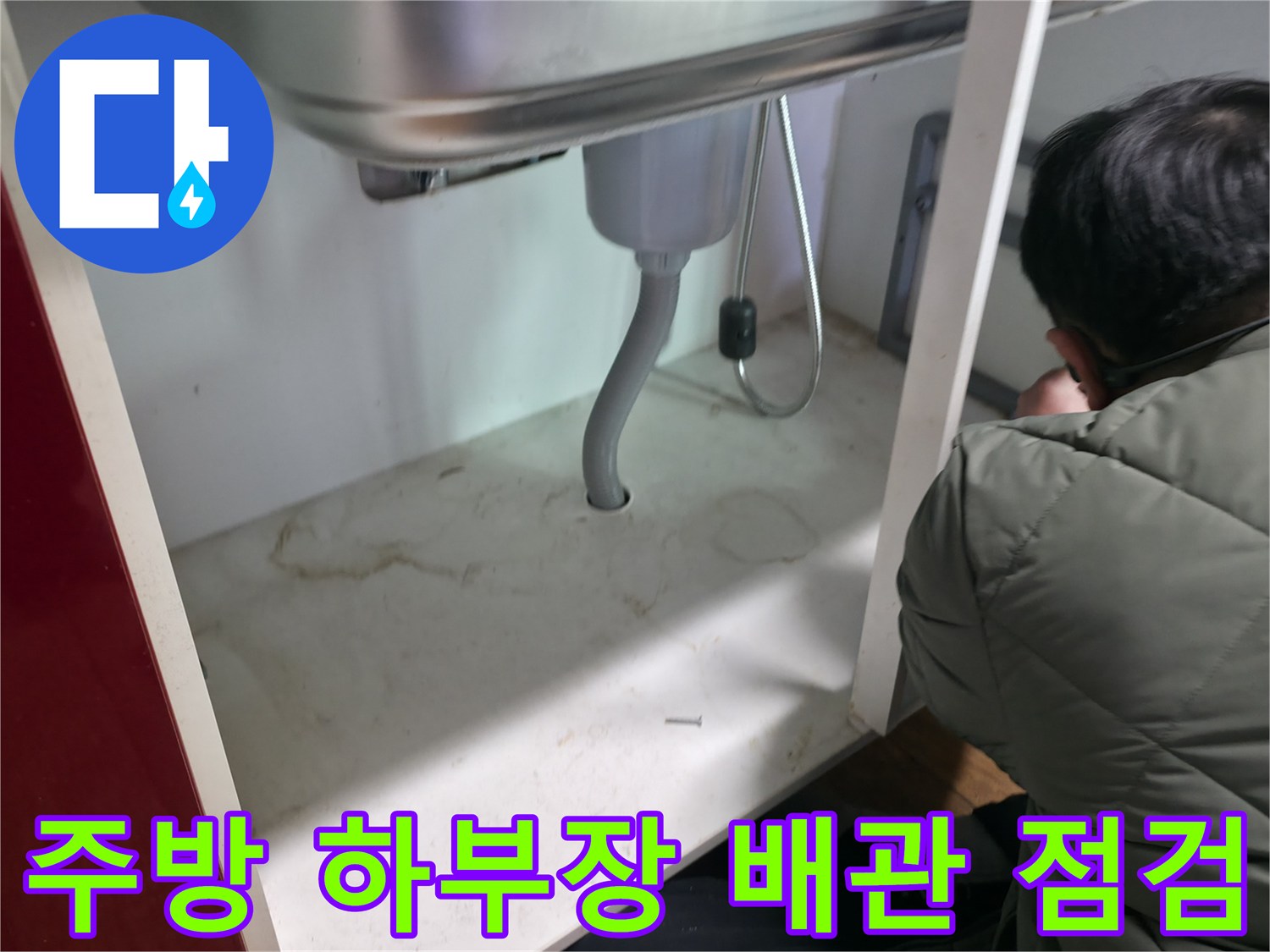 싱크대 밑 은색 주름관 및 연결 부위의 누수 흔적을 조사하는 모습