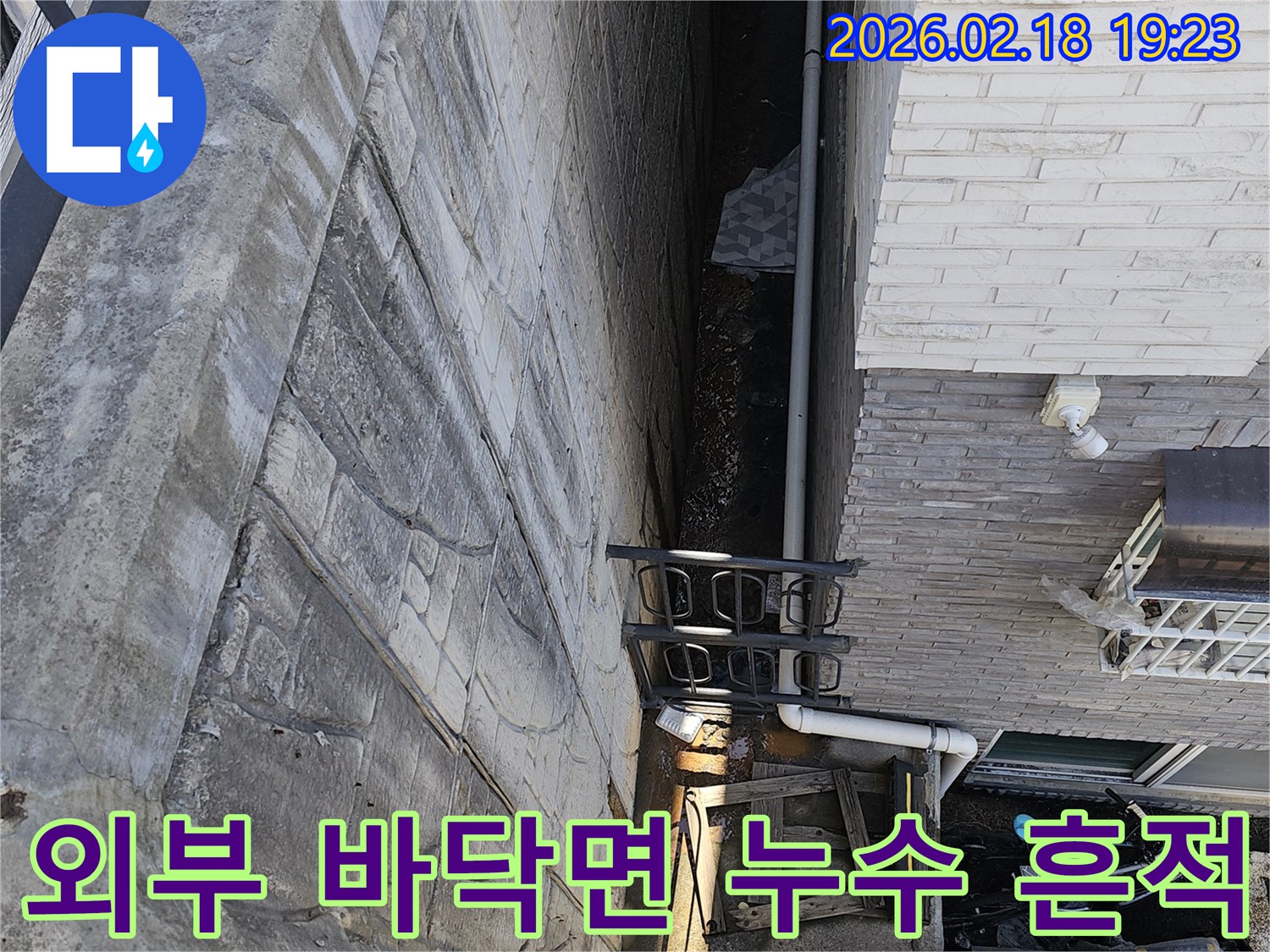 고양시 숲속마을 주택 외부 공간 바닥면에서 발견된 누수 흔적을-전문가가 정밀하게 분석하고 있는 현장 이미지입니다