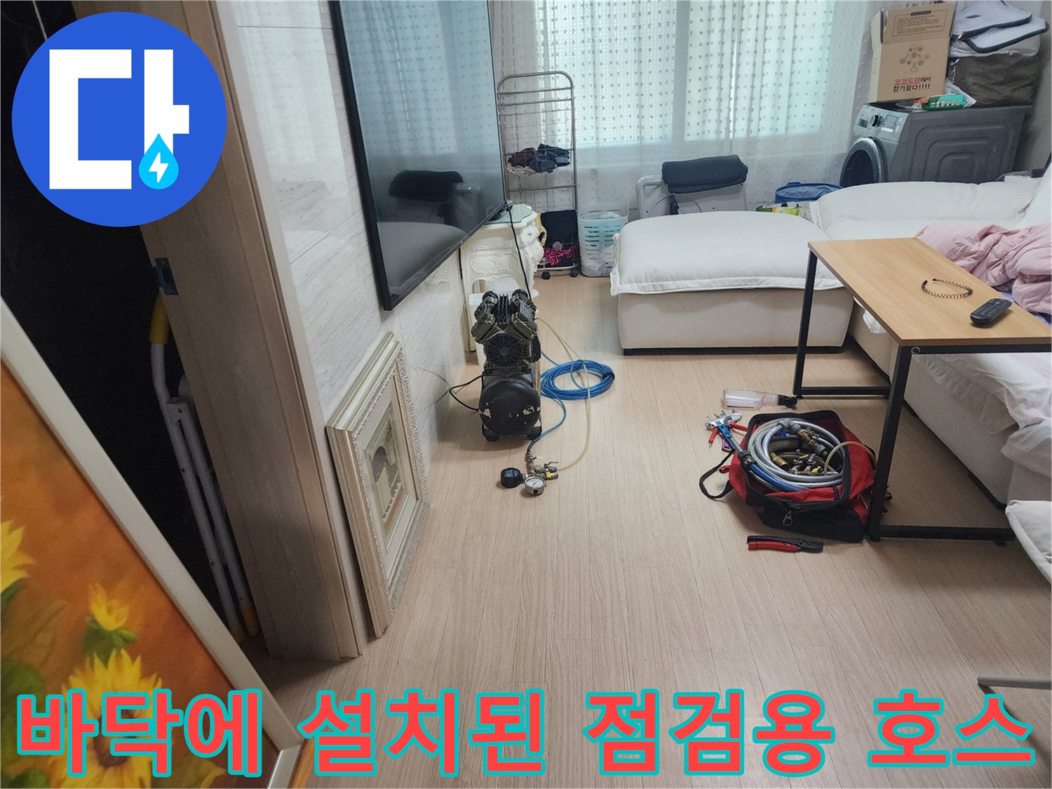 누수 탐지를 위해 거실 바닥에 배치된 파란색 호스와 압력 장비
