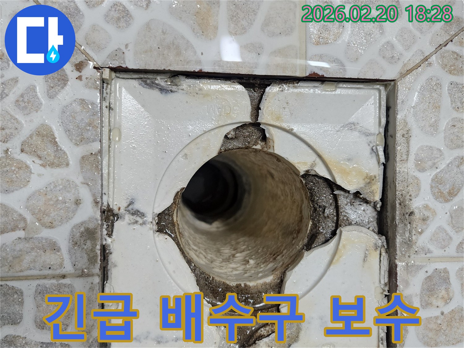 이 이미지는-욕실 배수구의 심각한 파손으로-배관이 노출되고-주변 방수층이 손상되어-물이 새는 현장을-보여주고 있습니다