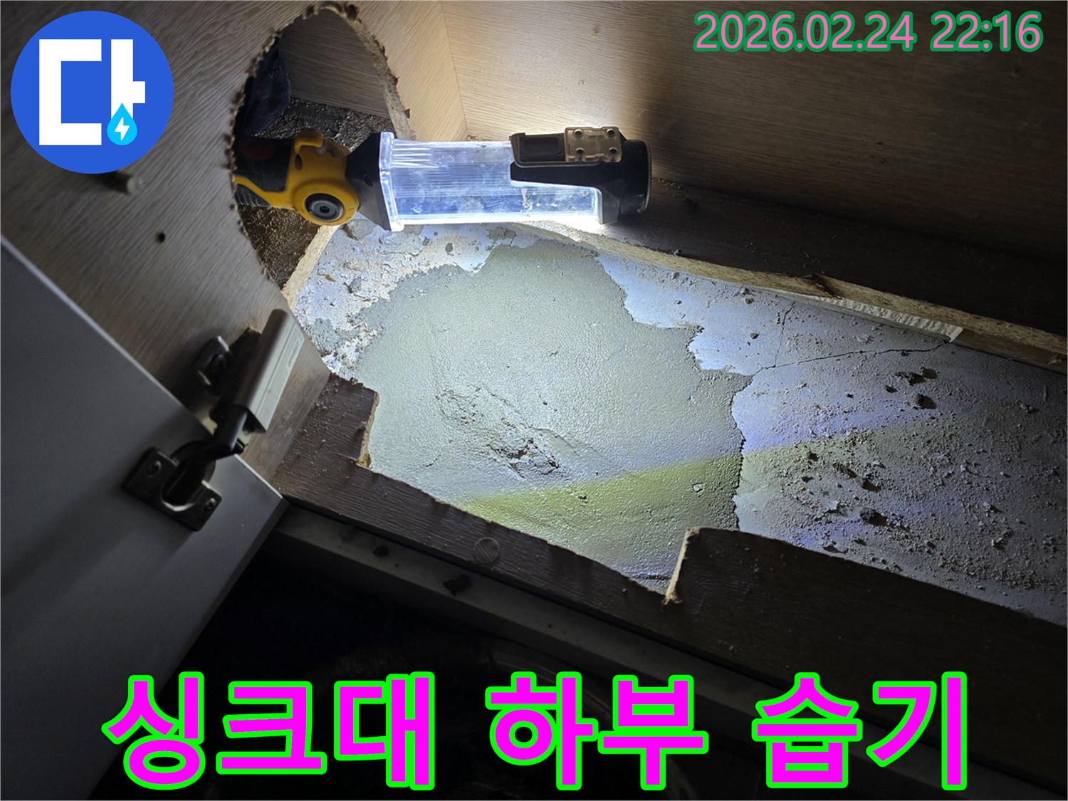 누수-엔지니어가-싱크대-하부의-습기-찬-공간을-조명으로-밝혀-누수-원인을-조사하는-현장
