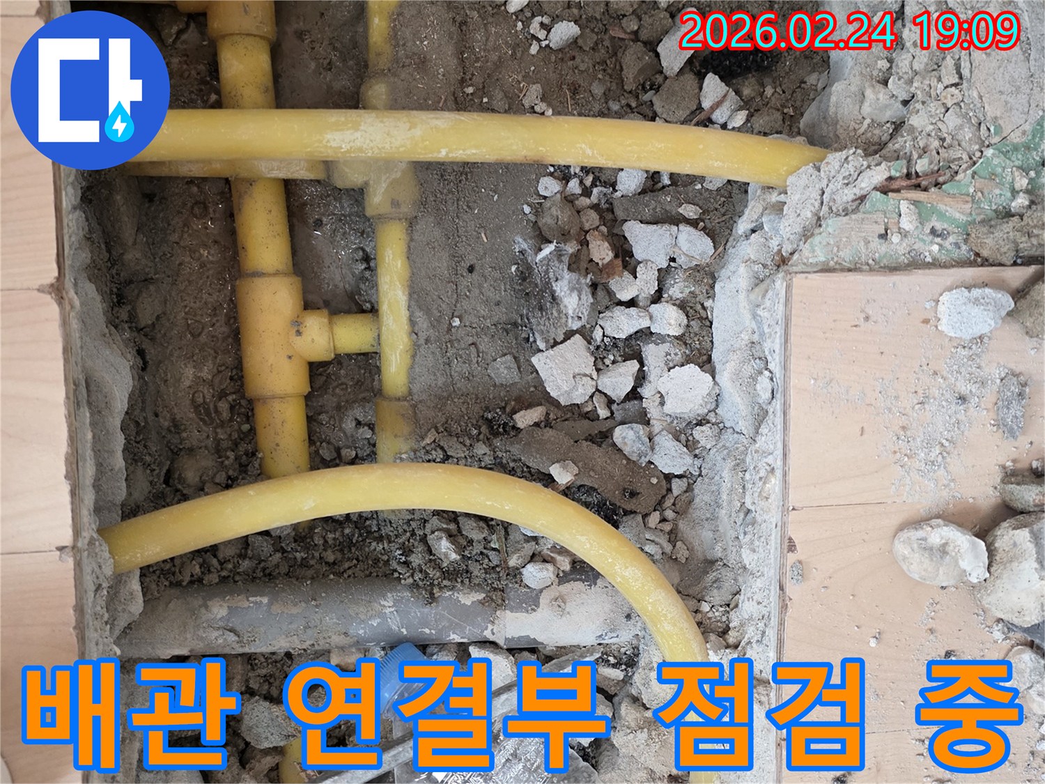 누수 원인 파악을 위해 바닥을 파쇄하고-노출된 배관의 연결 부위를-집중적으로 점검하는 작업 현장입니다.
