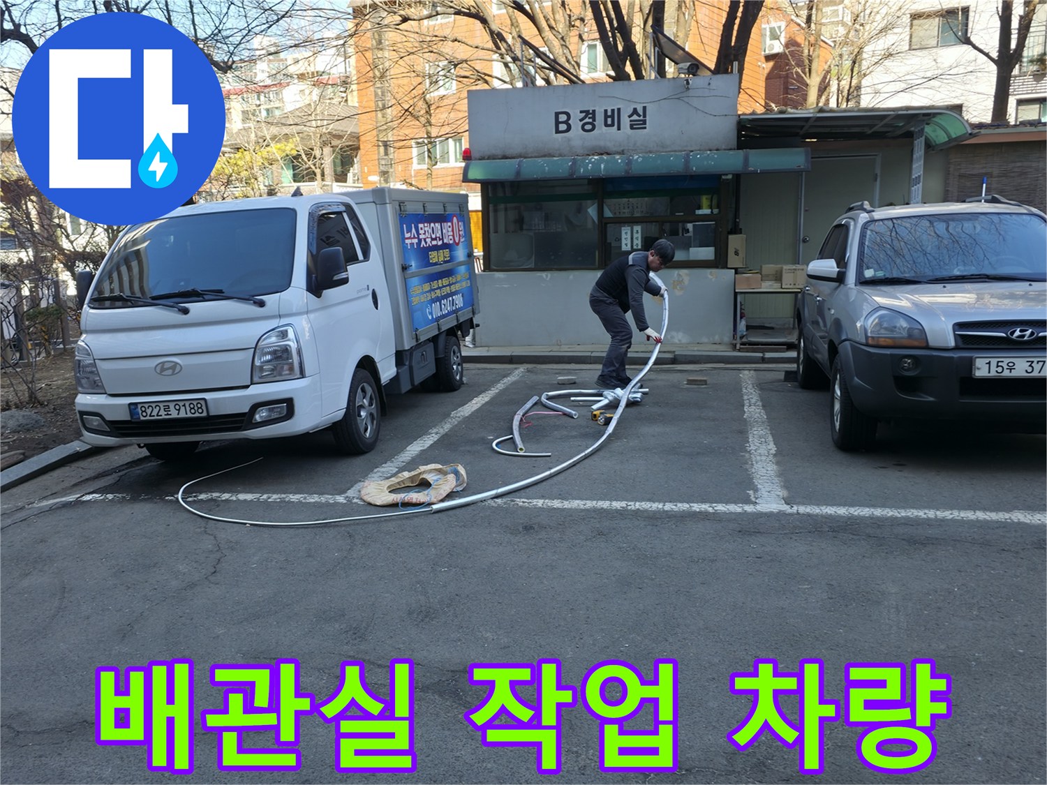강동구 아파트 지하 배관실 앞에 주차된 작업 차량과 장비 호스