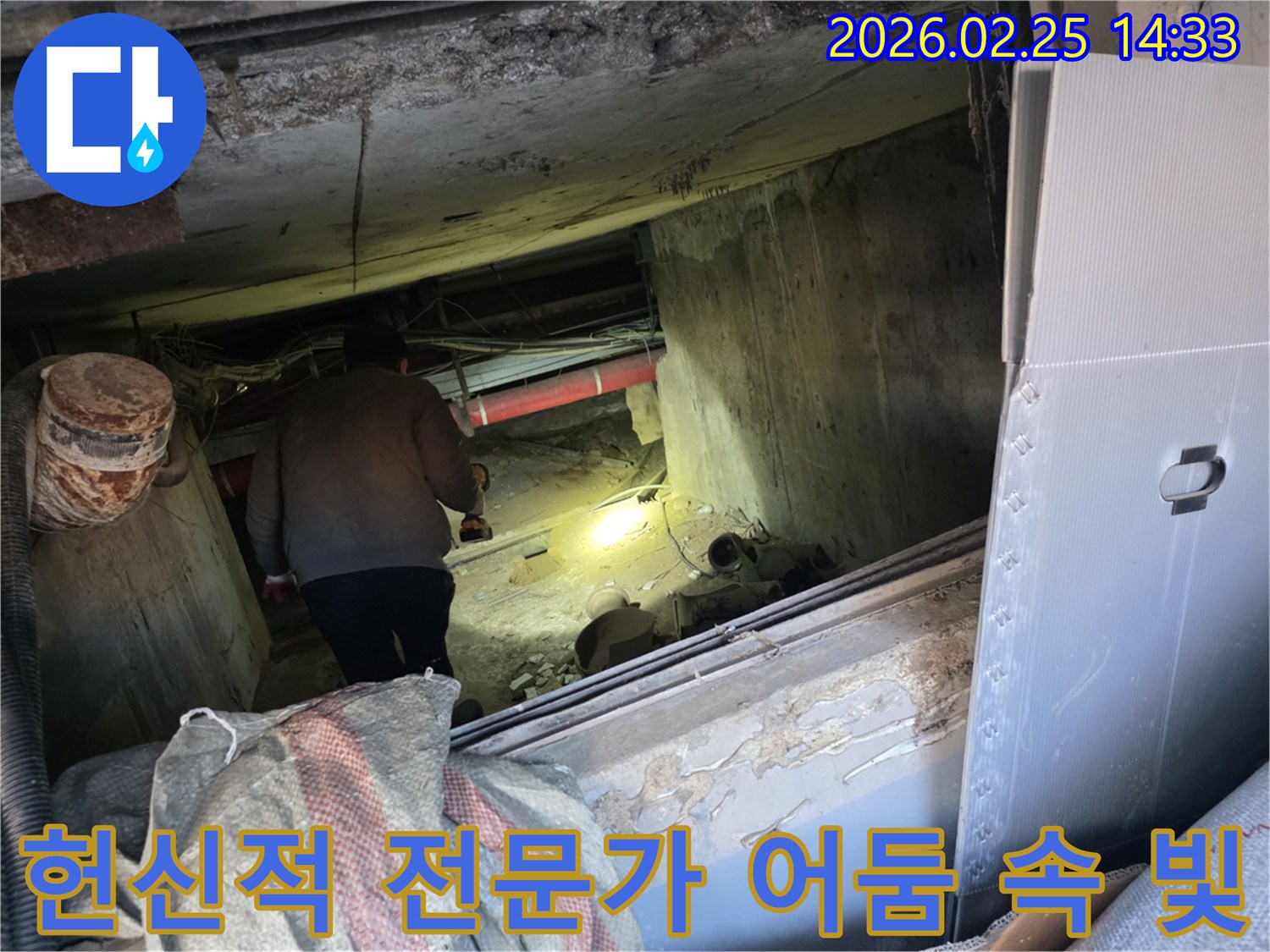 누수 전문 엔지니어가-어둡고 좁은 공간에서-손전등을 비춰가며-고객의 불편을 해소하기 위해-헌신적으로 누수 지점을-탐지하는 모습입니다.