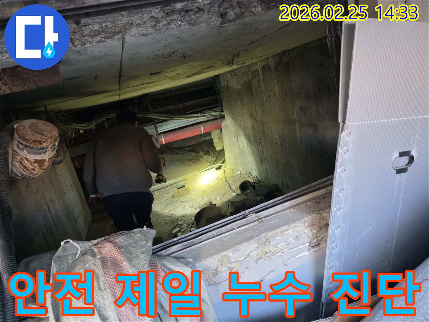 누수 전문 엔지니어가-어둡고 좁은 공간에서-안전 수칙을 준수하며-손전등을 비춰가며-누수 지점을 정확히-진단하는 모습입니다.