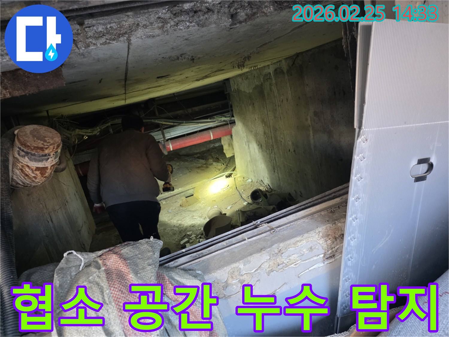 누수 전문 엔지니어가-어둡고 협소한 공간에서-손전등을 비춰가며-누수 지점을 끈기 있게-탐지하는 모습입니다.