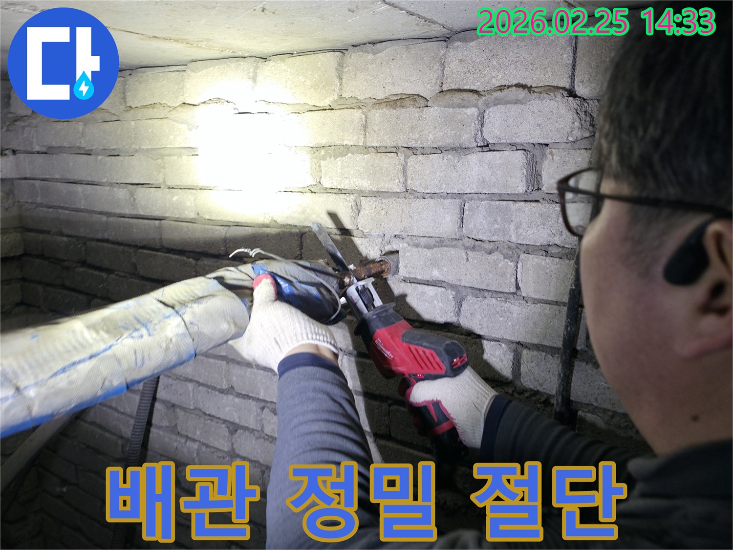 누수 전문가가-어두운 공간에서-랜턴을 비추며-손상된 배관을-정확히 절단합니다.