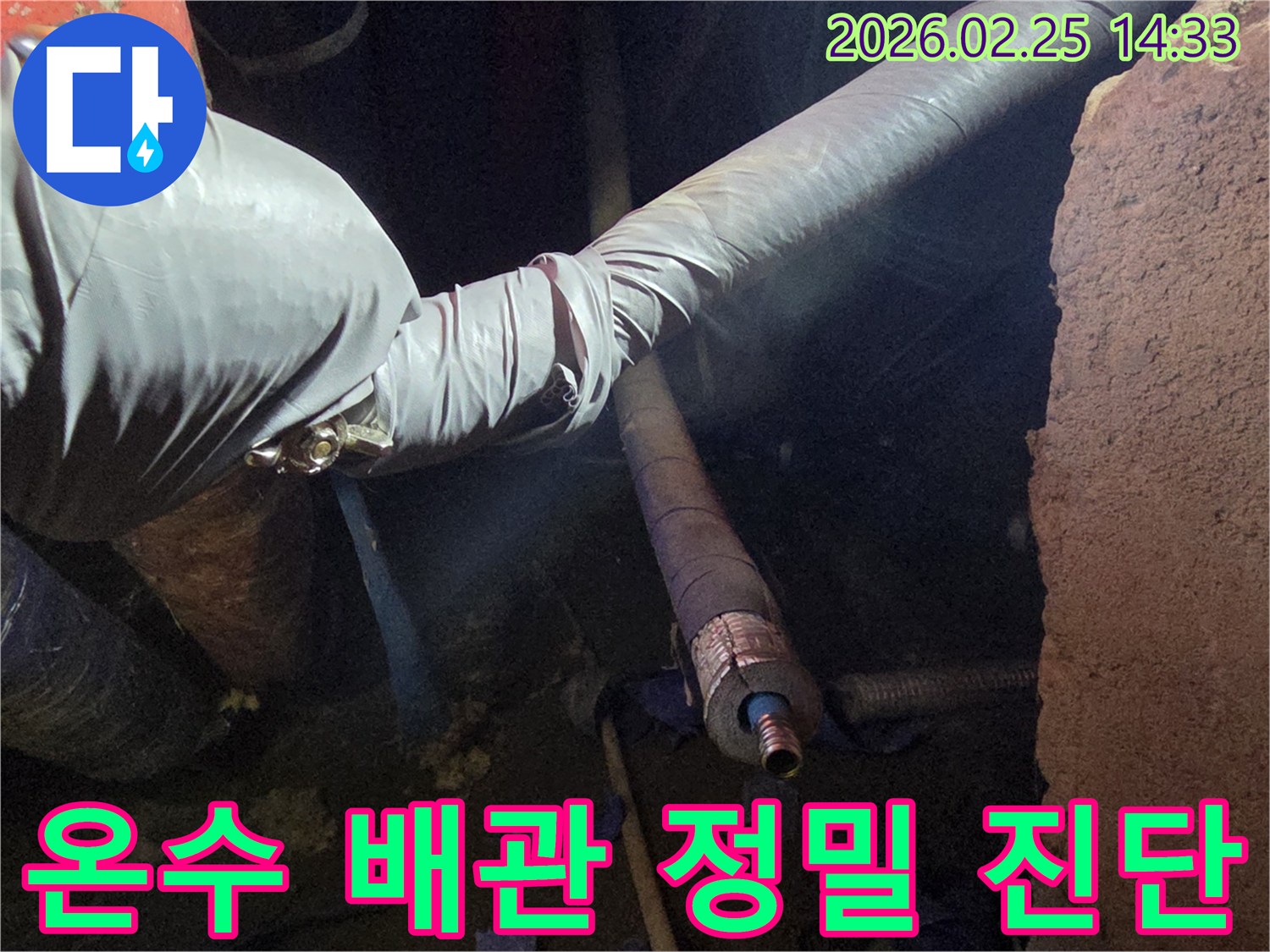 어두운 공간에서-숙련된 기술자가-장갑을 끼고-온수 배관의-손상된 연결 부위를-정밀하게 진단하는-모습입니다