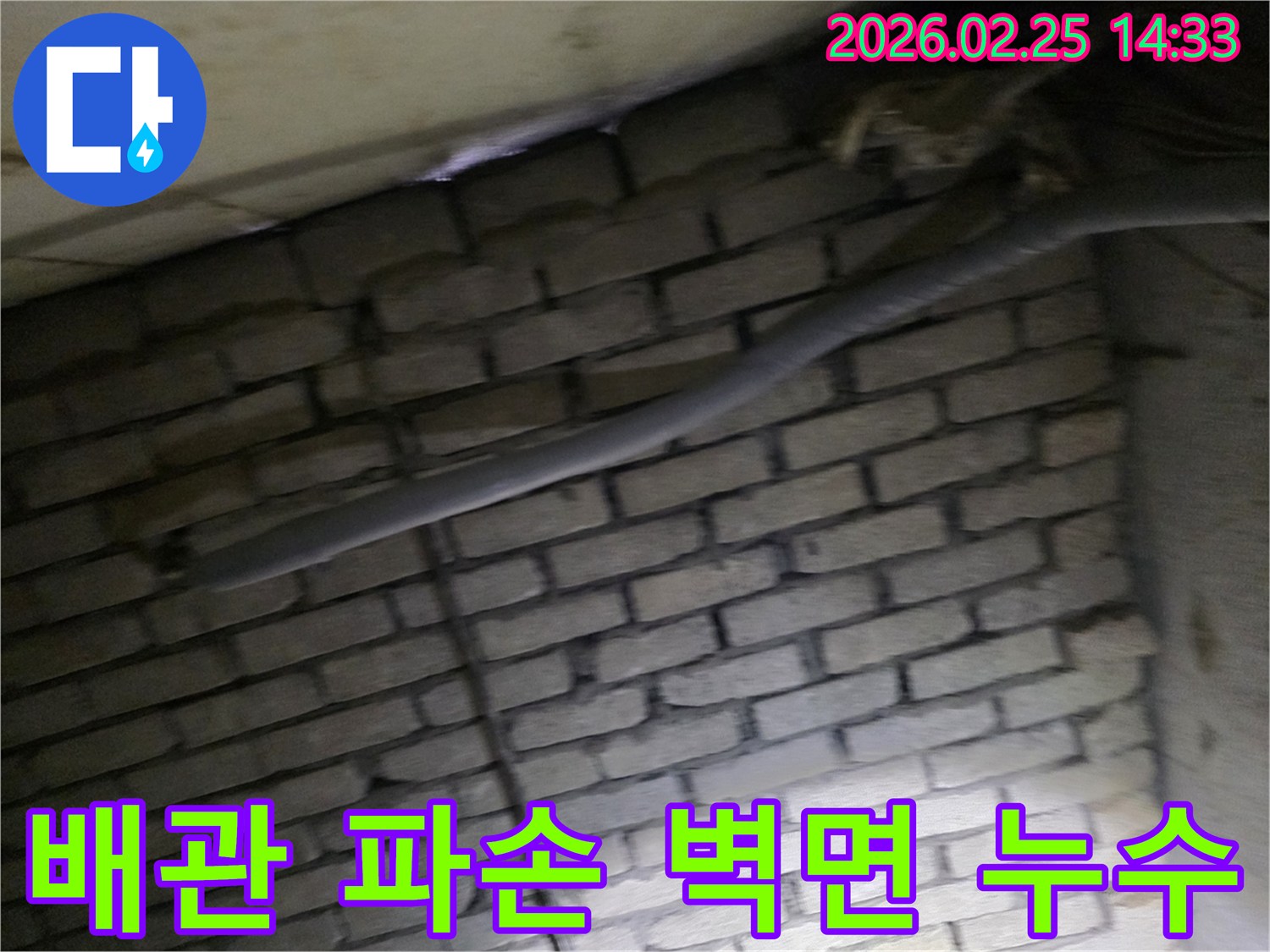 어두운 벽돌 벽면을 배경으로-단열된 배관과 함께-누수 여부를 확인하기 위해-정밀하게 검사되는 현장 모습입니다.