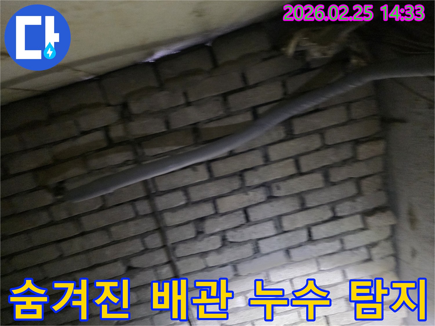 어두운 벽돌 벽면을 배경으로-단열된 배관과 함께-누수 여부를 확인하기 위해-정밀하게 검사되는 현장 모습입니다.