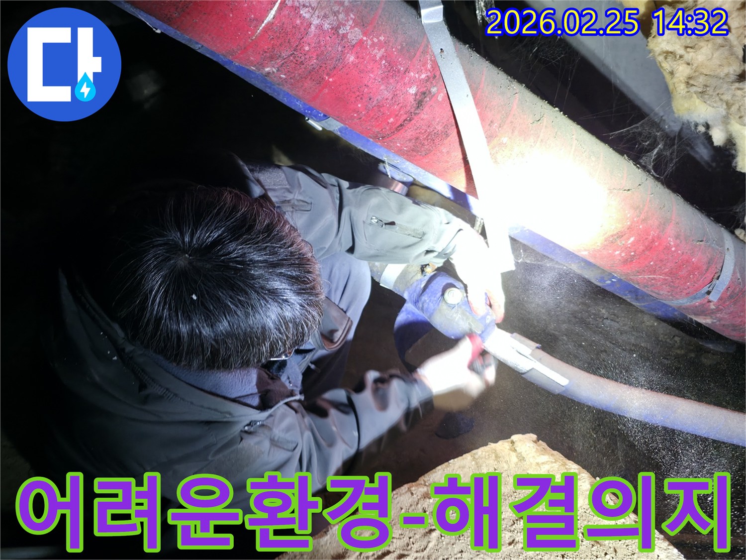 전문 엔지니어가-어둡고 좁은 어려운 환경 속에서-작업등을 비추며-누수 문제를-해결하려는 강한 의지를 보여주고 있습니다