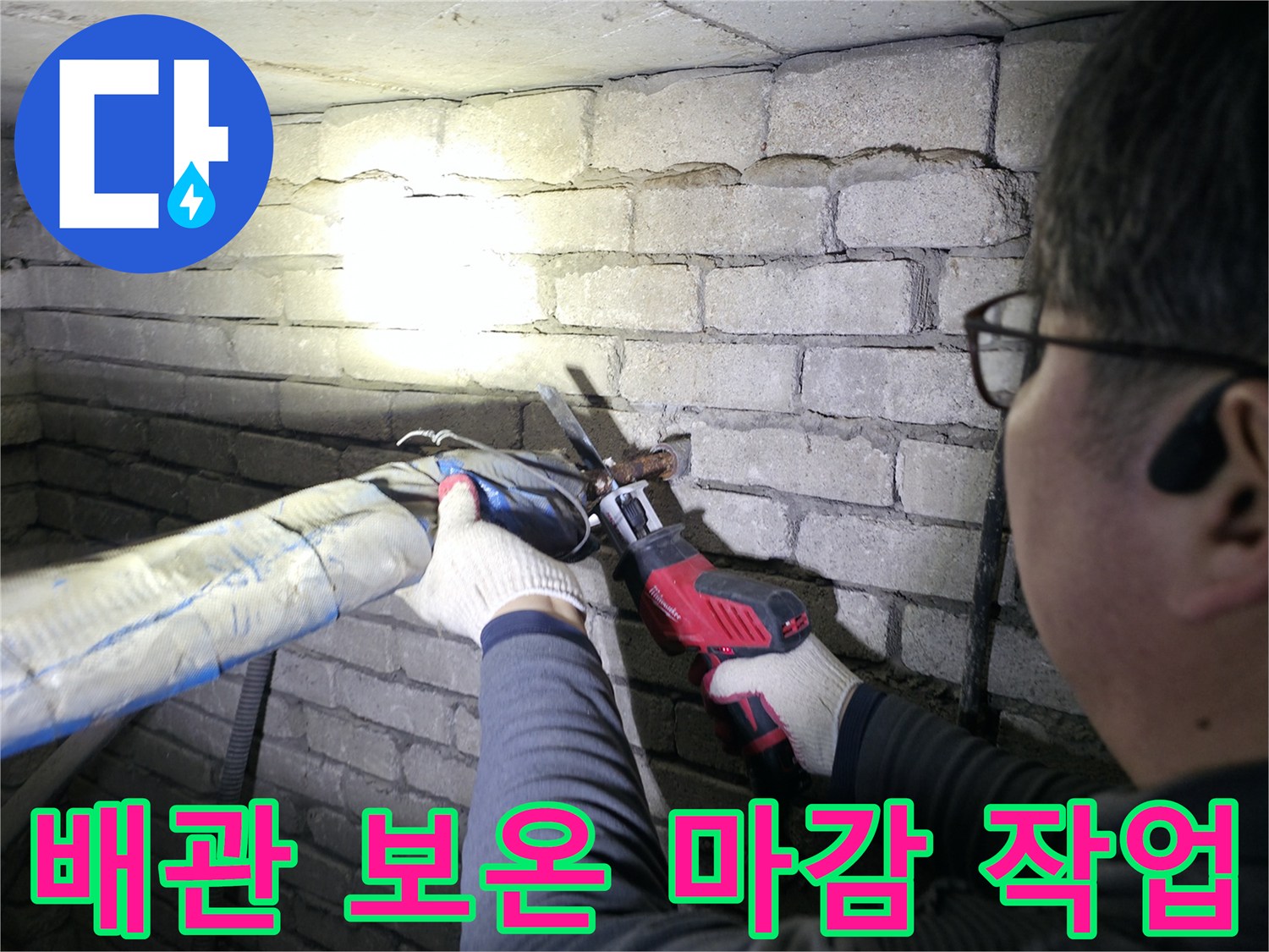 지하 배관실의 은색 보온재로 감싸진 배관을 테이프로 꼼꼼하게 마감하는 모습