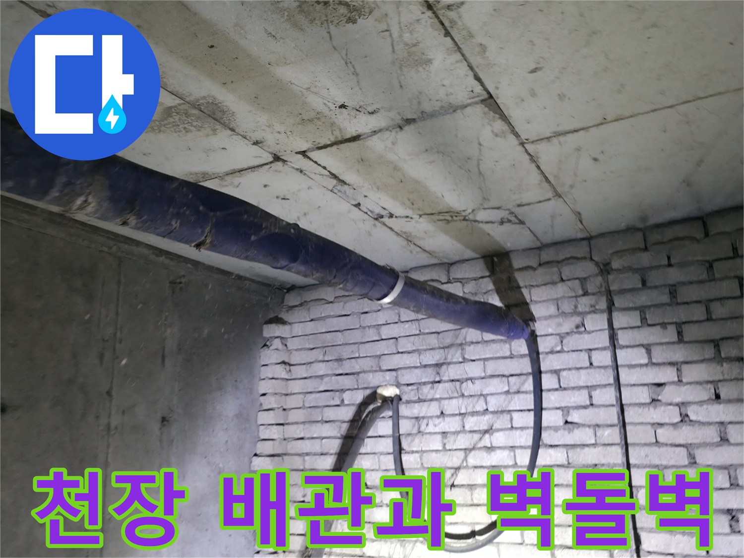 하얀 벽돌 구조물 위를 지나가는 파란색 보온재 배관