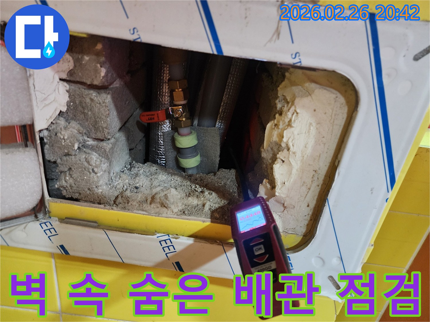 누수 탐지 엔지니어가-특수 장비로-배관 주변의 습기를 측정하며-누수 지점을 찾는 장면