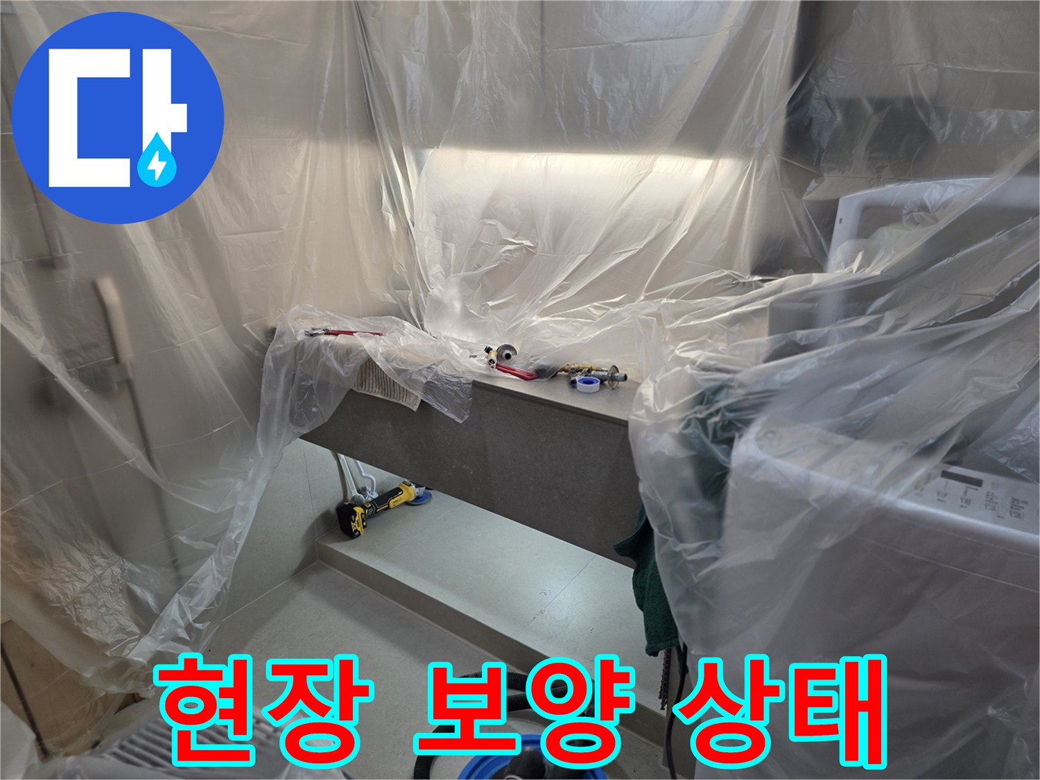 비닐로 덮인 작업 구역과 전동 드릴이 놓인 모습-배관 수리 준비