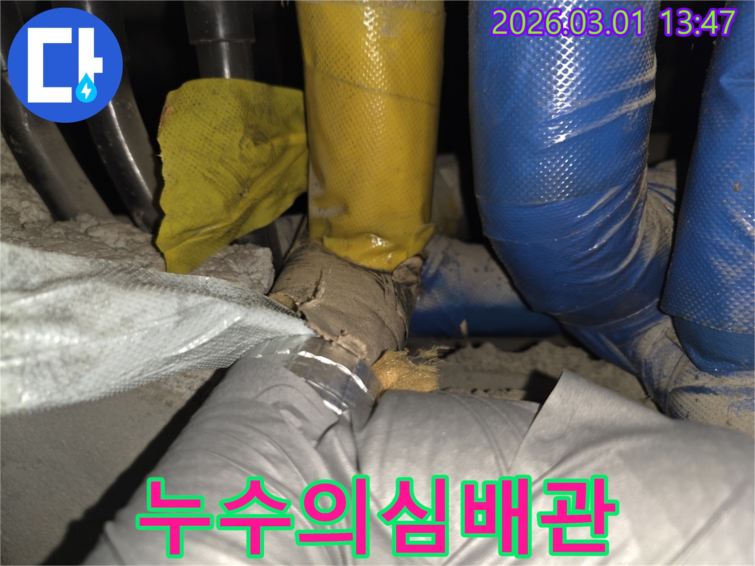 노후화된 배관의 보온재가 파손되어-에너지 손실과 누수 위험이 있는 장면입니다.