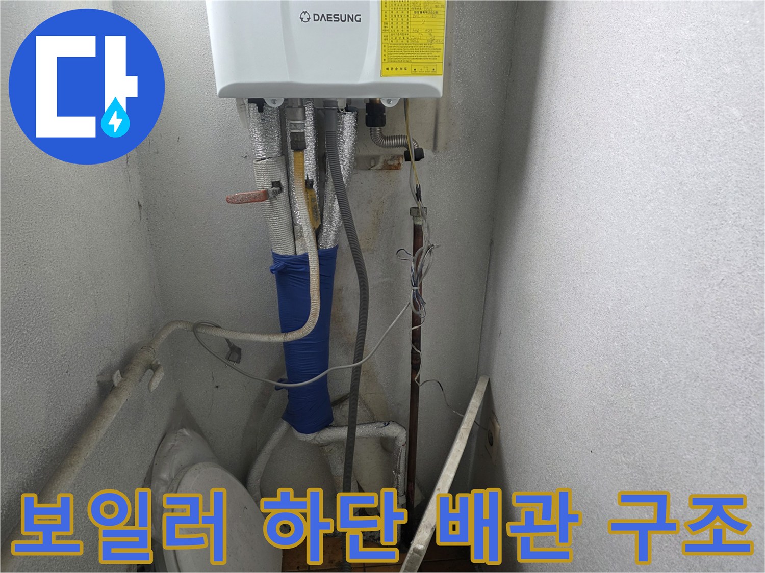 보일러 아래쪽의 다양한 배관들과 수전 연결 부위 근접 촬영