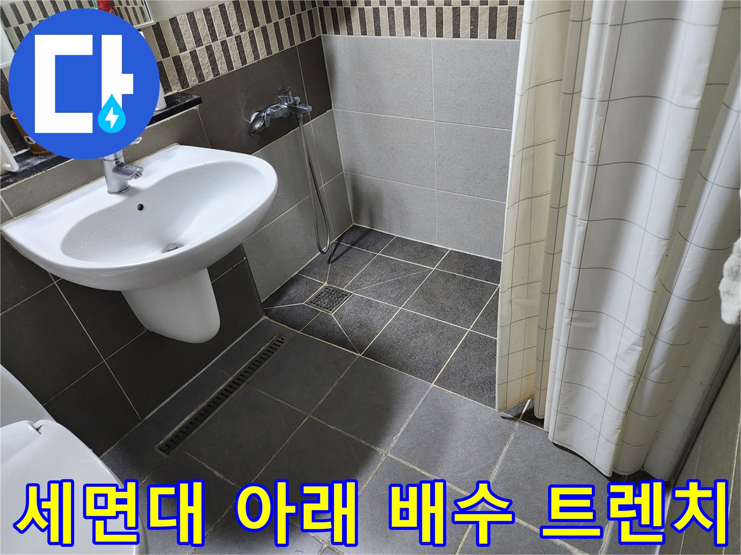 욕실 세면대 하단부 타일과 배수구 주변 모습