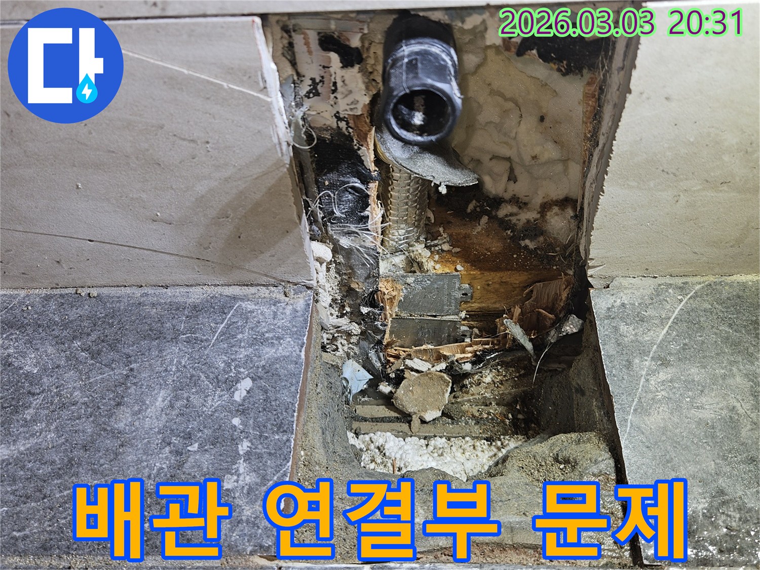 벽면 타일이 제거된 공간에서-누수 원인으로 지목된 배관의 연결 부위가 노출되어 있는 현장 사진