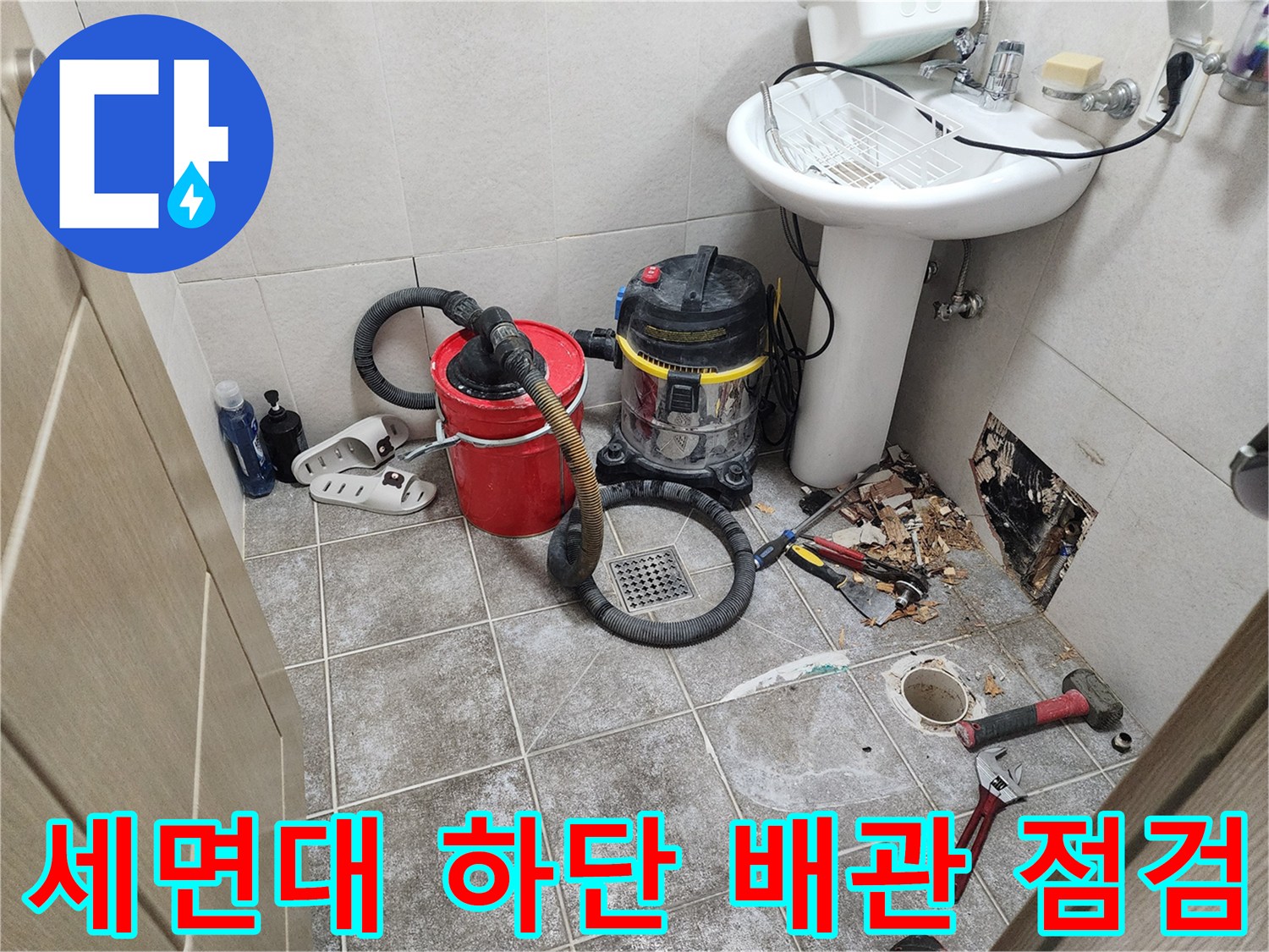 세면대 아래쪽-노출된 벽체 내부의 누수 흔적과 공구들