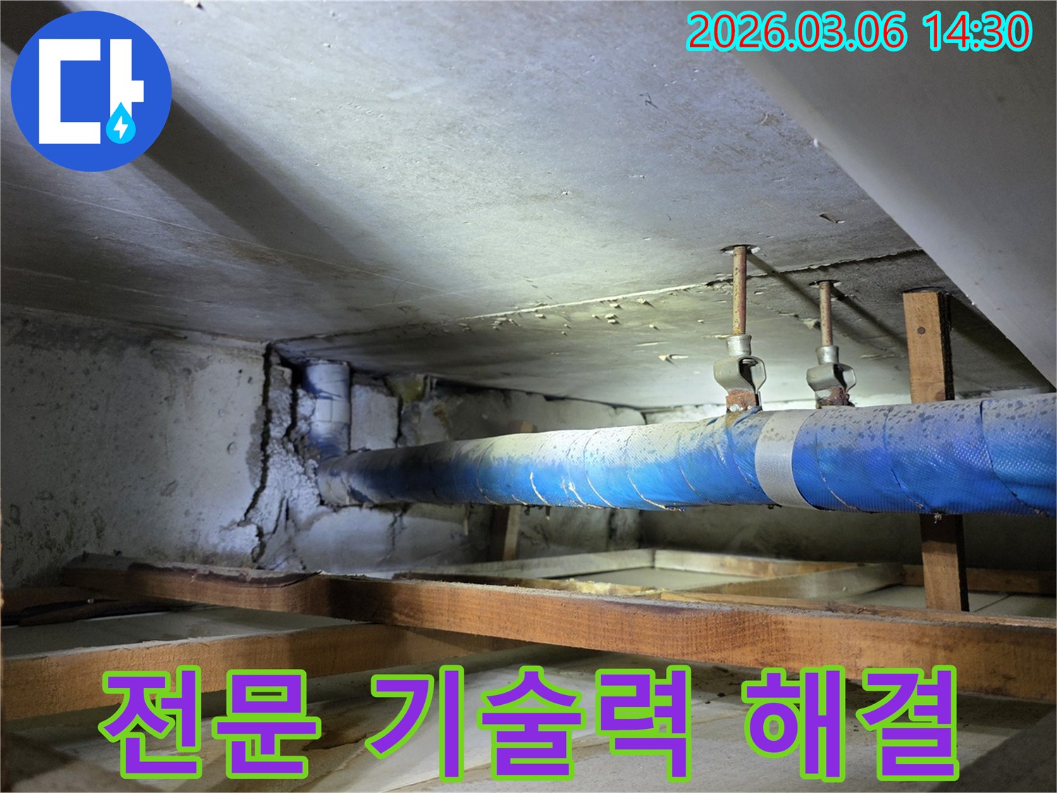 지하 공간의 파란색 배관과-손상된 콘크리트 벽면을-누수 엔지니어가-전문 기술력으로-완벽하게 해결하기 위한-방안을 모색하는 모습
