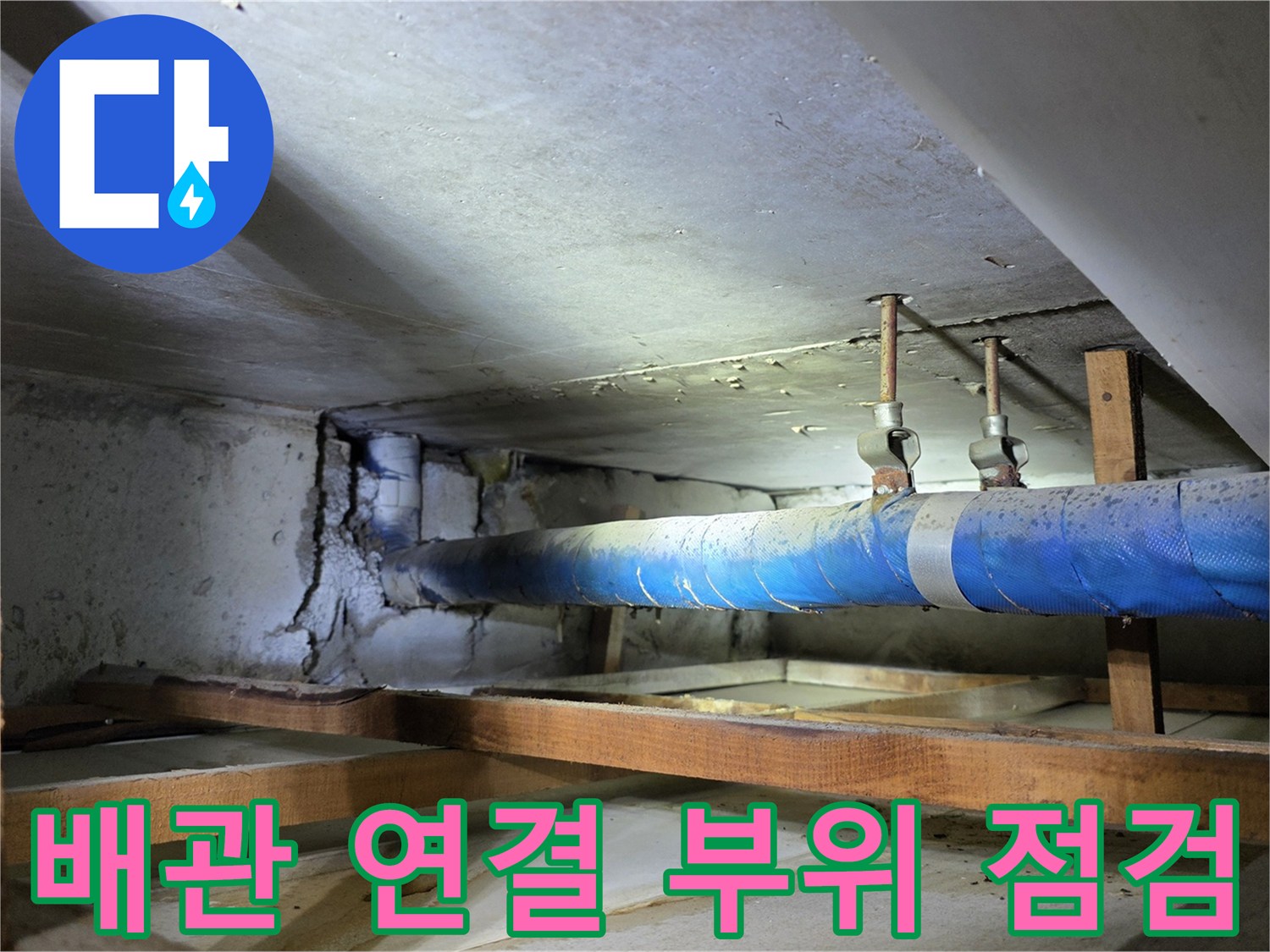 파란색 보온재가 감긴 배관과 천장 목재 구조물 근접 사진
