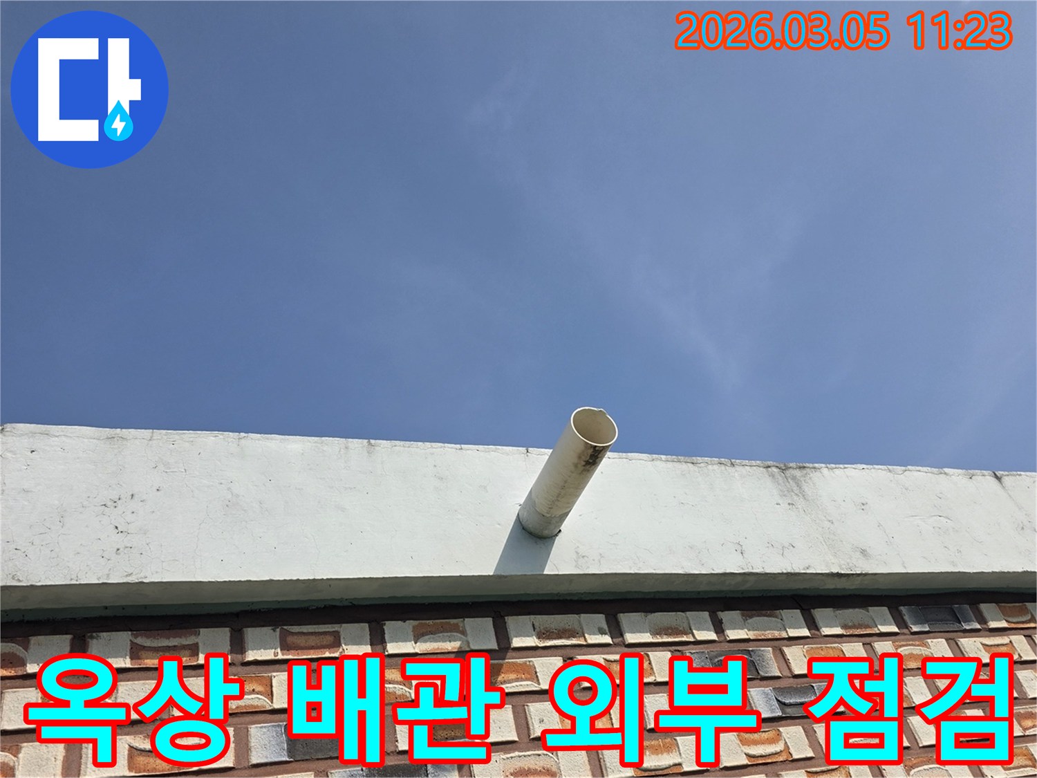 푸른-하늘을-배경으로-옥상-난간에서-돌출된-배수관의-모습을-촬영한-사진입니다.