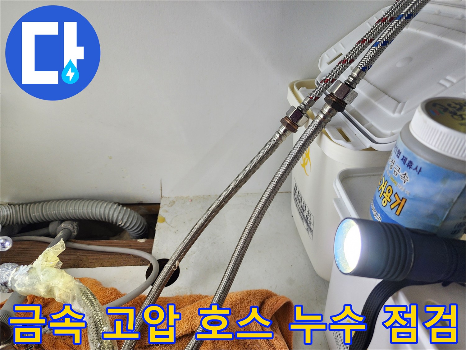 손전등 빛에 비춰진 싱크대 하단 금속 배관 연결부