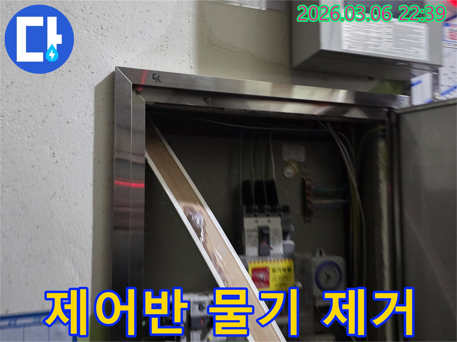 이 이미지는 전기 제어반 내부로 유입된 물기를-제거하고 있는 현장을 보여주며-안전한 전기 사용을 위한-복구 작업의 중요성을 강조합니다.