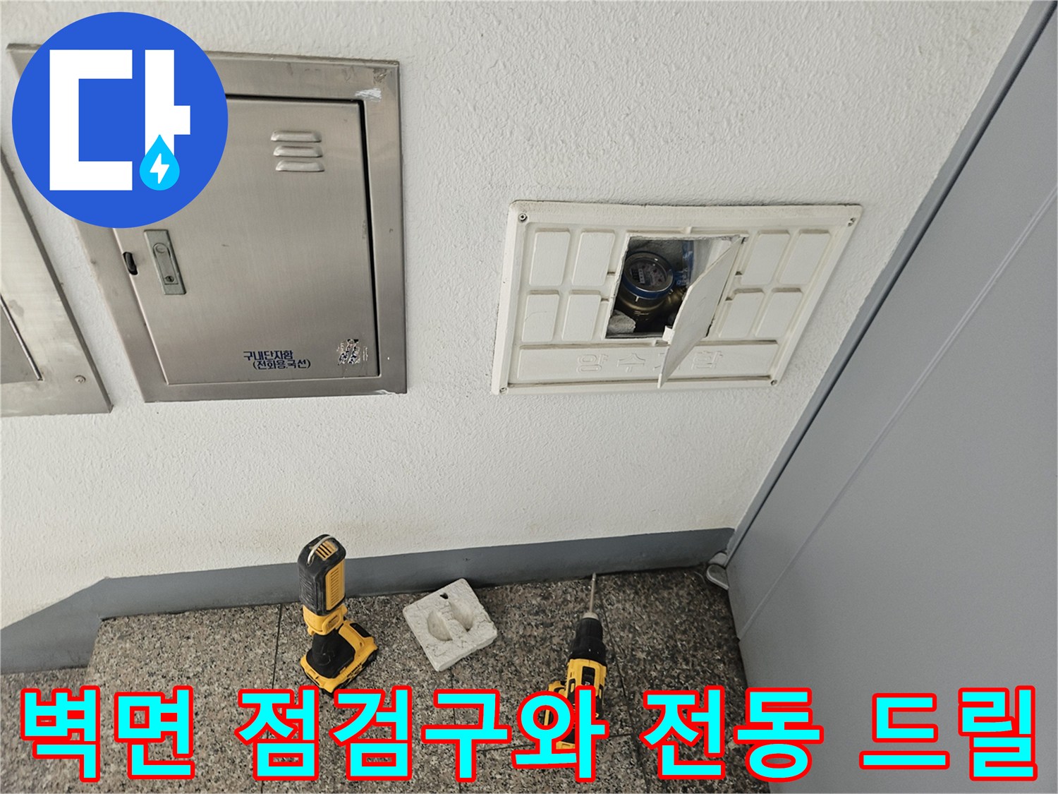 배관 수리를 위해 벽면 점검구 앞에 놓인 작업 도구들