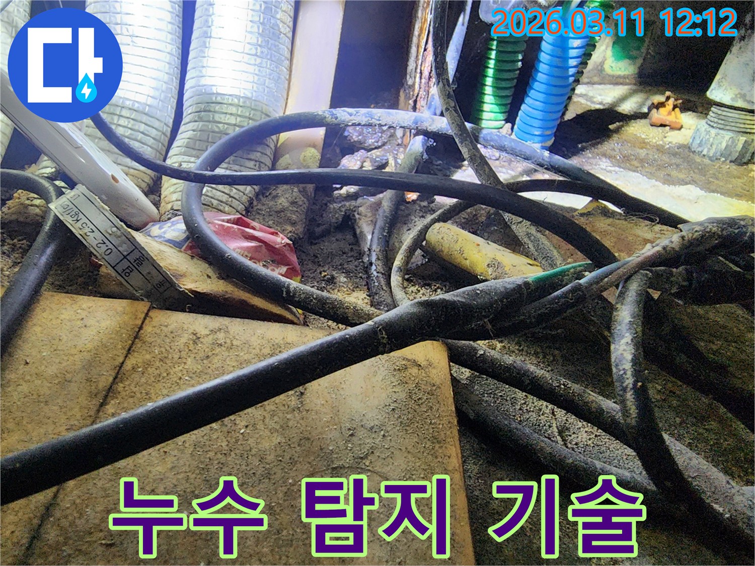 누수-공사 현장에서-복잡하게-얽힌-배관과-전선-사이의-오염된-모습을-담은-사진입니다.