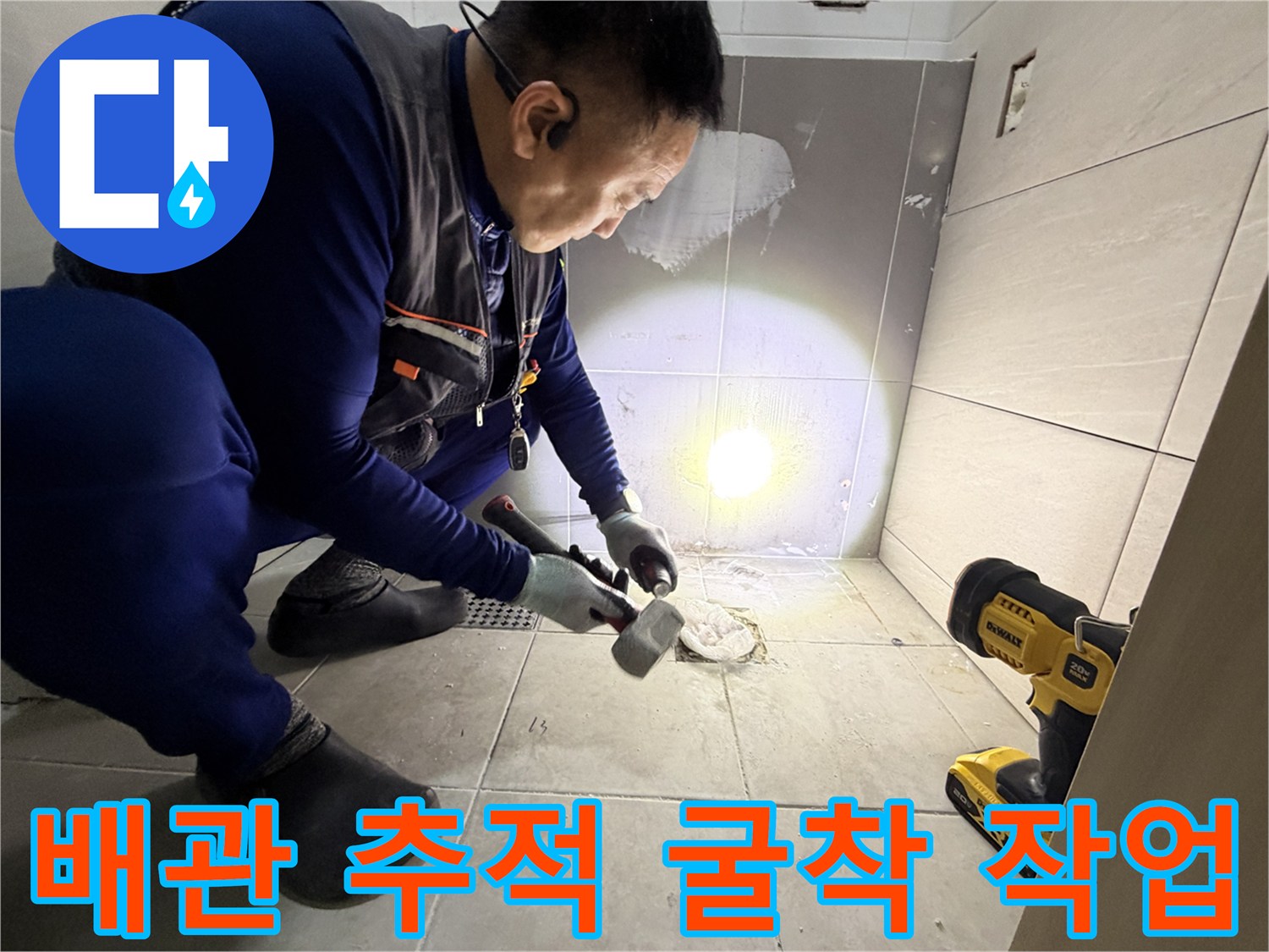 공구와 손전등을 사용하여-화장실 바닥 배관 부위를 점검하는 모습