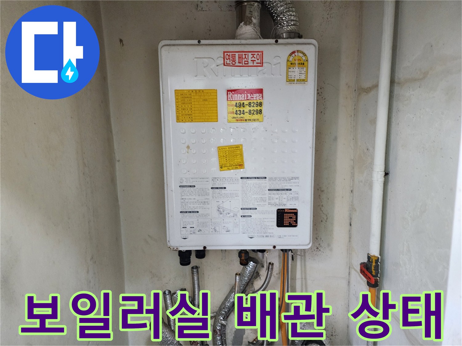 보일러 하단에 연결된 여러 개의 금속 배관과 분배기 모습입니다.