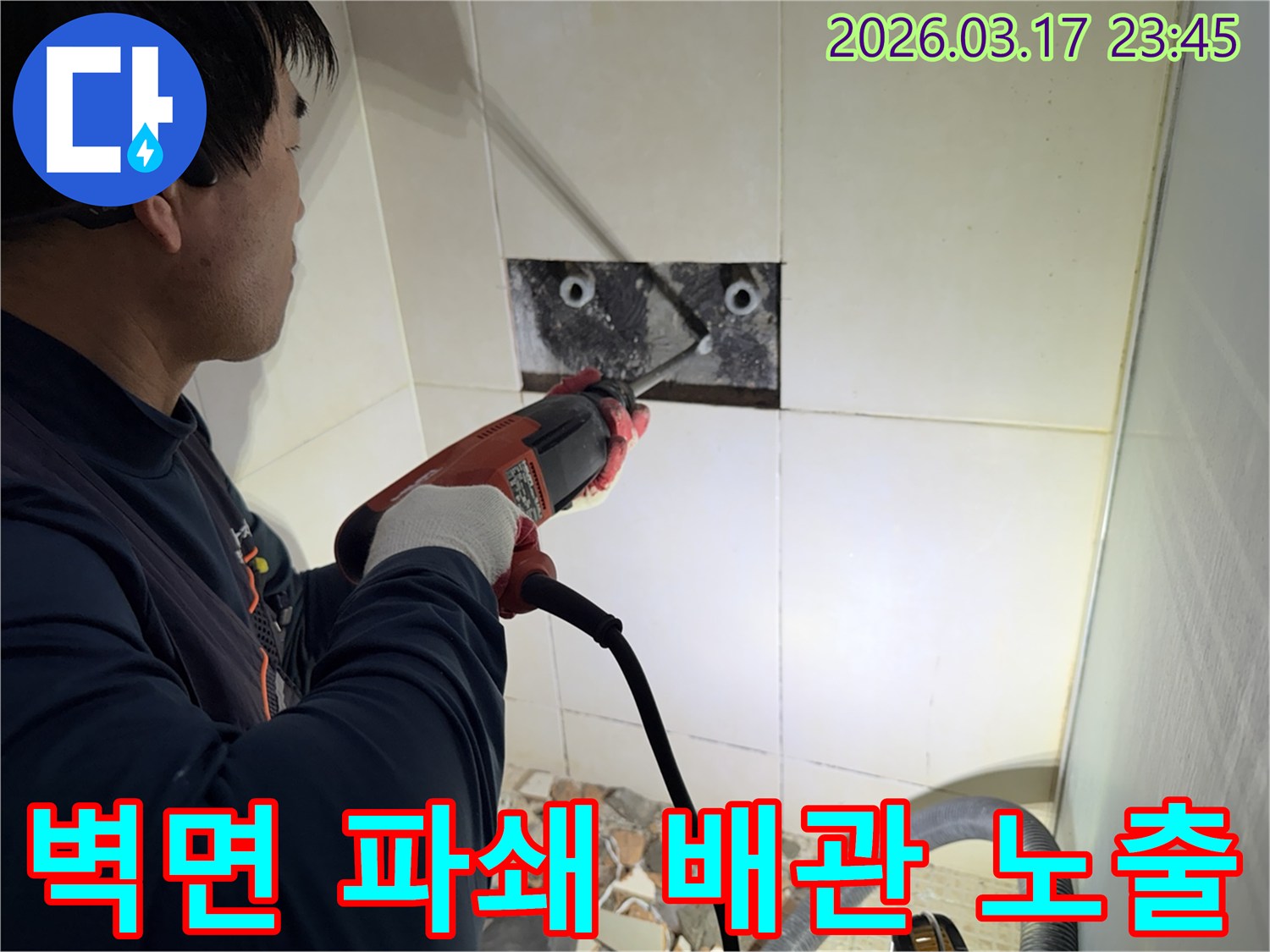 누수 공사 전문가가 욕실 벽면의 타일을 조심스럽게 파쇄하여-누수 원인을 찾기 위한 배관 노출 작업을 진행하는 모습입니다.