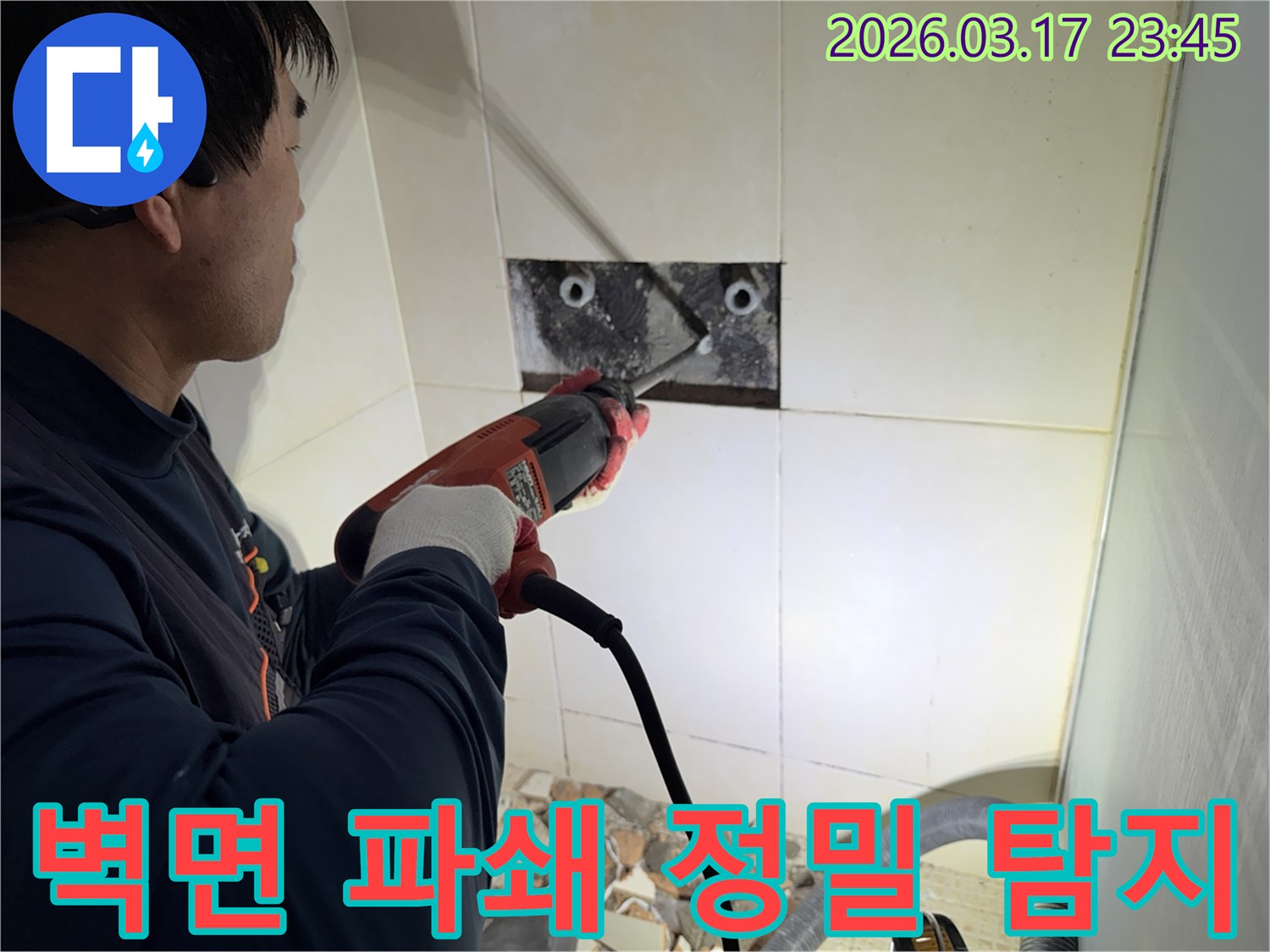 누수 공사 전문가가 욕실 벽면의 타일을 조심스럽게 파쇄하여-누수 원인을 찾기 위한 배관 확인 작업을 진행하는 모습입니다.