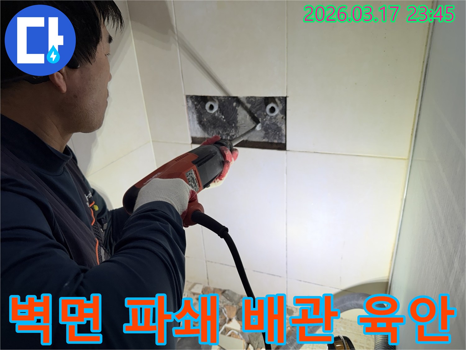 누수 전문가가 벽면 타일을 깨끗하게 파쇄하며-누수 원인인 배관의 문제점을 육안으로 검사하는 작업을 진행 중입니다.